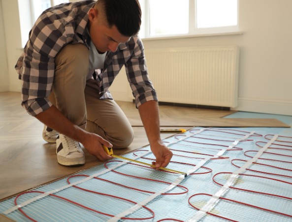 Instalador midiendo y verificando la solera antes de colocar tarima sobre suelo radiante