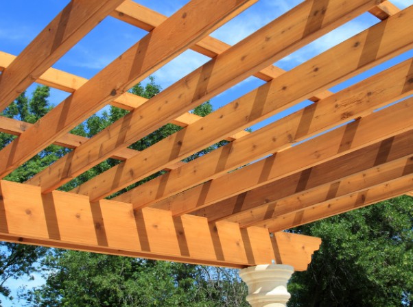 Vigas y correas de madera de una pérgola abierta vistas a contraluz